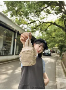 Stijlvolle kaki mini nylon rugzak vastgehouden door een vrouw in een lichte straat buiten.