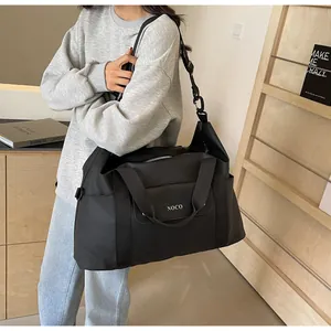 Detailopname van een grote zwarte reistas gedragen door een model in een casual setting