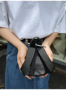 Close-up van zwart driehoekig nylon tasje met brede geweven riem en karabijnhaak.