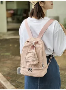 Detail van een stijlvolle lichtroze 2-in-1 nylon rugzak gedragen door een model.