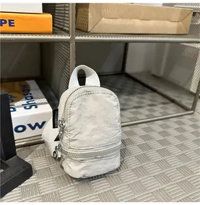 Detailweergave van een mini witte accessoiretas van kreukelstof met zilveren ritssluitingen