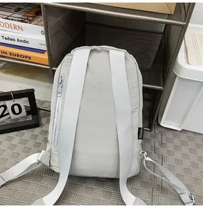 Gedetailleerd achteraanzicht van een minimalistische lichtgrijze nylon rugzak met brede riemen