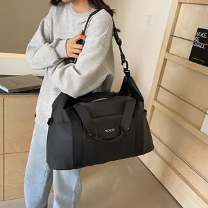 Stijlvolle grote zwarte nylon reistas met NOCO-logo, getoond door een vrouwelijk model