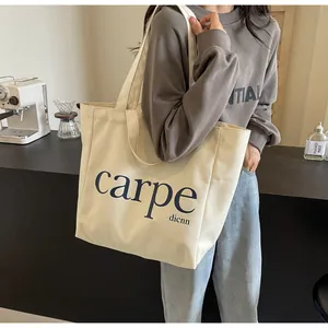 Lifestyle shot of a woman carrying a large minimalist cream canvas tote bag with carpe text