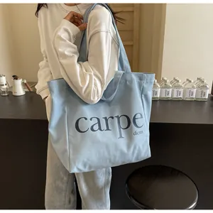 Stylish large light blue canvas tote bag with carpe print shown worn on shoulder
