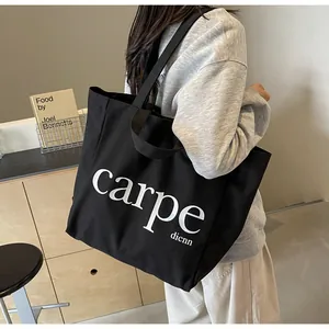 Close-up of black canvas tote bag with white carpe lettering carried on shoulder
