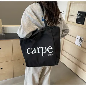 Detailed view of black canvas tote bag with carpe dicnn print worn by model