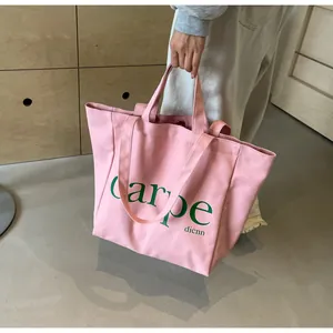 Close-up of a pink large capacity canvas tote bag with green carpe text design