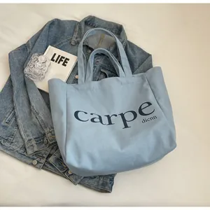 Detailed view of a light blue canvas tote bag with carpe print and denim jacket