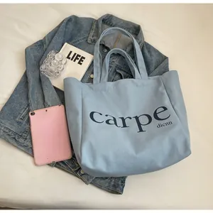Detailed shot of a light blue canvas tote bag featuring carpe print on a casual background