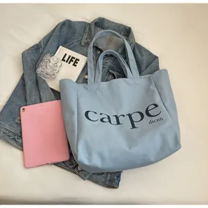 Minimalist light blue canvas tote bag with black carpe text in lifestyle scene