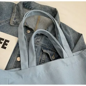 Close-up detail of a light blue canvas tote bag showing reinforced handles and stitching.
