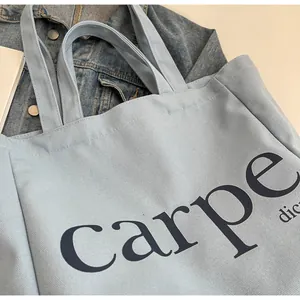 Detailed close-up shot of light blue canvas tote bag with carpe diem printed text