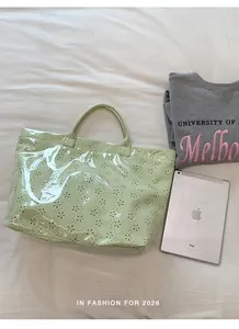Détail d'un sac cabas en gelée PVC imperméable vert clair avec des motifs ajourés de fleurs.