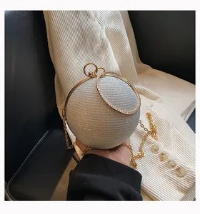 Close-up of silver glitter spherical evening bag with elegant gold ring handles and chain.