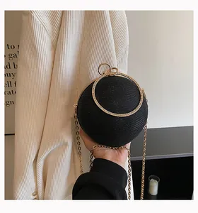 Close-up of a sparkling black spherical evening clutch with gold circular handle