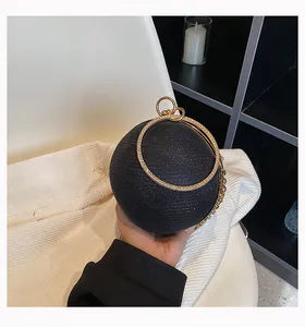 Close-up of a black spherical evening clutch with a gold crystal-encrusted ring handle.