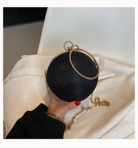 Detail view showing the sparkling texture of a black sphere clutch with gold ring handle
