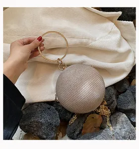 Detail of a spherical evening clutch bag with sparkling diamond texture and gold handle.
