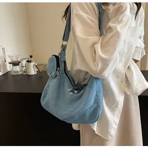 Woman carrying a large capacity blue denim tote bag in a minimalist indoor setting
