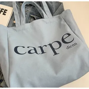 Close-up view of a minimalist light blue canvas tote bag featuring 'carpe' printed text
