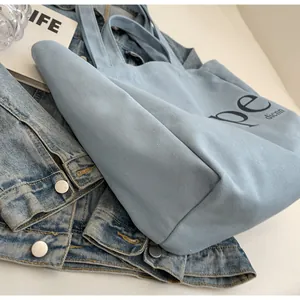 Close-up detail of light blue canvas tote bag on a denim jacket backdrop for students