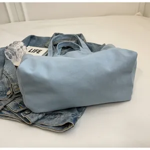 Detailed view of the bottom structure of this large light blue canvas tote bag.