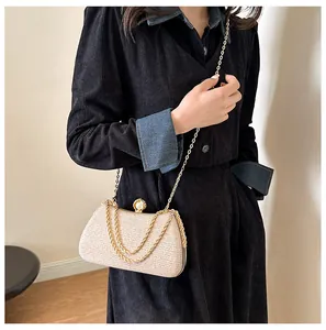 Elegant shimmery champagne evening clutch bag with gold chain strap shown on model.