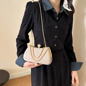 Detail view of champagne glitter evening bag held by model wearing a dark corduroy dress