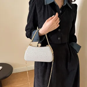 Detailed shot of an elegant silver glitter evening clutch bag with gold chain strap