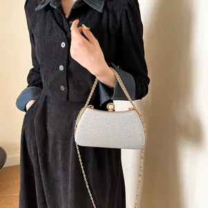 Close-up of a sparkling silver hard-shell evening clutch with a gold chain strap.
