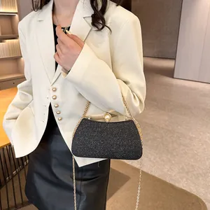 Close-up of a sparkling black evening clutch with gold chain strap on a model