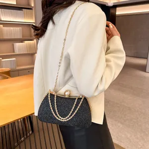 Detailed view of elegant black glitter evening clutch with gold chain strap on model