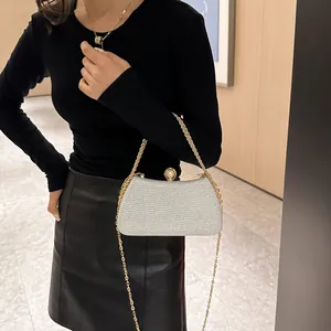 Detail of silver sparkly evening clutch with gold chain held by model in black outfit