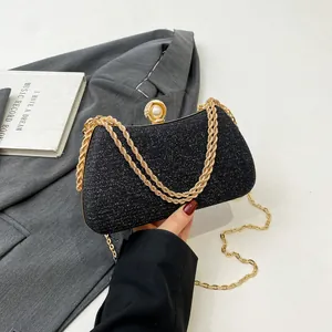 Elegant black glitter evening clutch bag featuring a golden chain and pearl clasp detail