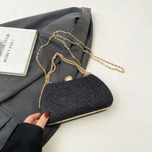 Detailed view of an elegant black glitter evening clutch bag with gold chain strap