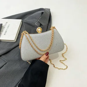 Detailed view of silver shimmering evening clutch with gold chain and pearl clasp