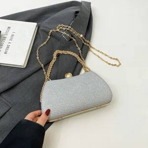 Detailed view of silver glitter evening clutch bag with pearl clasp and gold chains