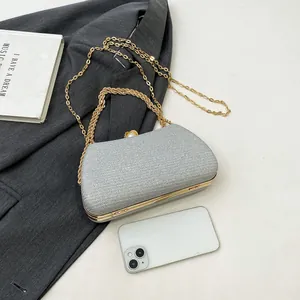 Silver glitter evening clutch with gold chain strap shown with a smartphone