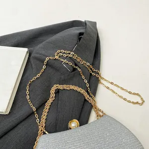 Close-up detail of silver glitter evening bag with gold chain and pearl clasp.