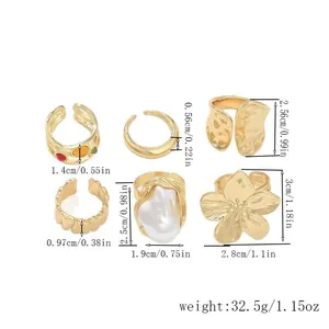 Detailansicht von sechs goldfarbenen offenen Ringen mit Lavatextur und Blumen