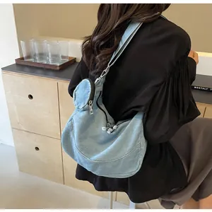 Detailed view of a light blue denim tote bag worn as a shoulder bag on a model