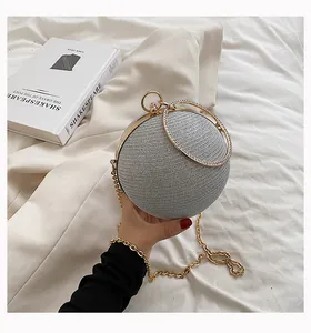 Detail view of silver sphere evening bag with rhinestone double handle and gold strap.