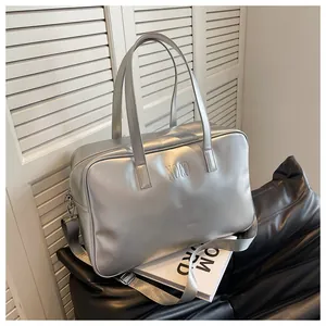 Detail van een zilveren metallic reistas met NOCO-branding en verstelbare schouderriem