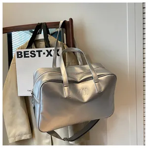 Detailweergave van de grote zilveren metallic reistas met NOCO-branding in lifestyle-zetting