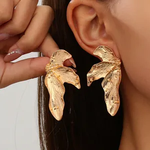 Macro view showing the intricate texture of gold leaf alloy earrings on a model's ear