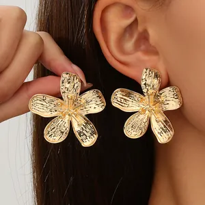 Detailed view of oversized vintage gold five-petal flower earrings with textured metal finish