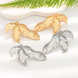 Close-up macro view of vintage leaf-shaped earrings in gold and silver finish