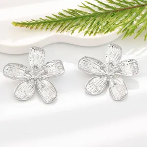 Detailed close-up of silver five-petal flower earrings with textured finish