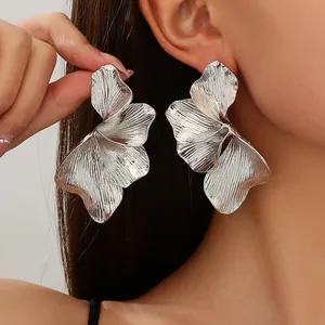 Close-up of silver double-layer flower earrings with textured striped leaf design.